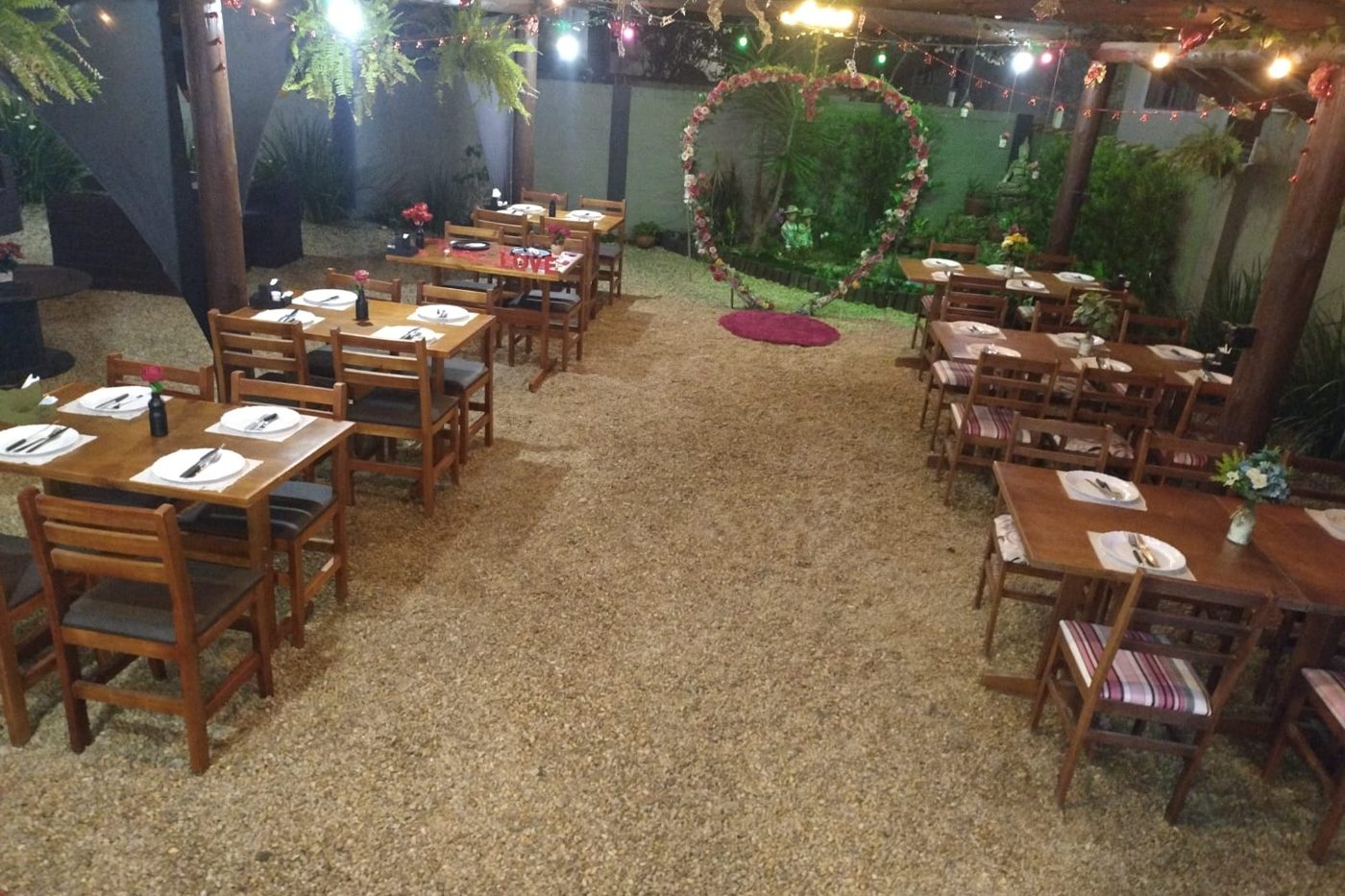 Área externa do Deck House com mesas e luzes à noite
