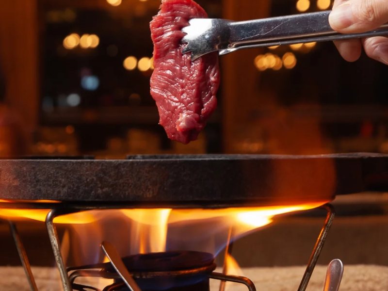 Carne sendo grelhada na pedra quente